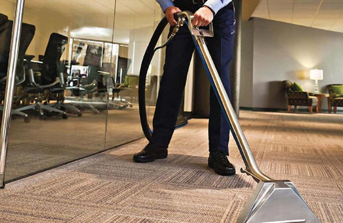 A professional cleaning commercial carpet using cleaning equipment